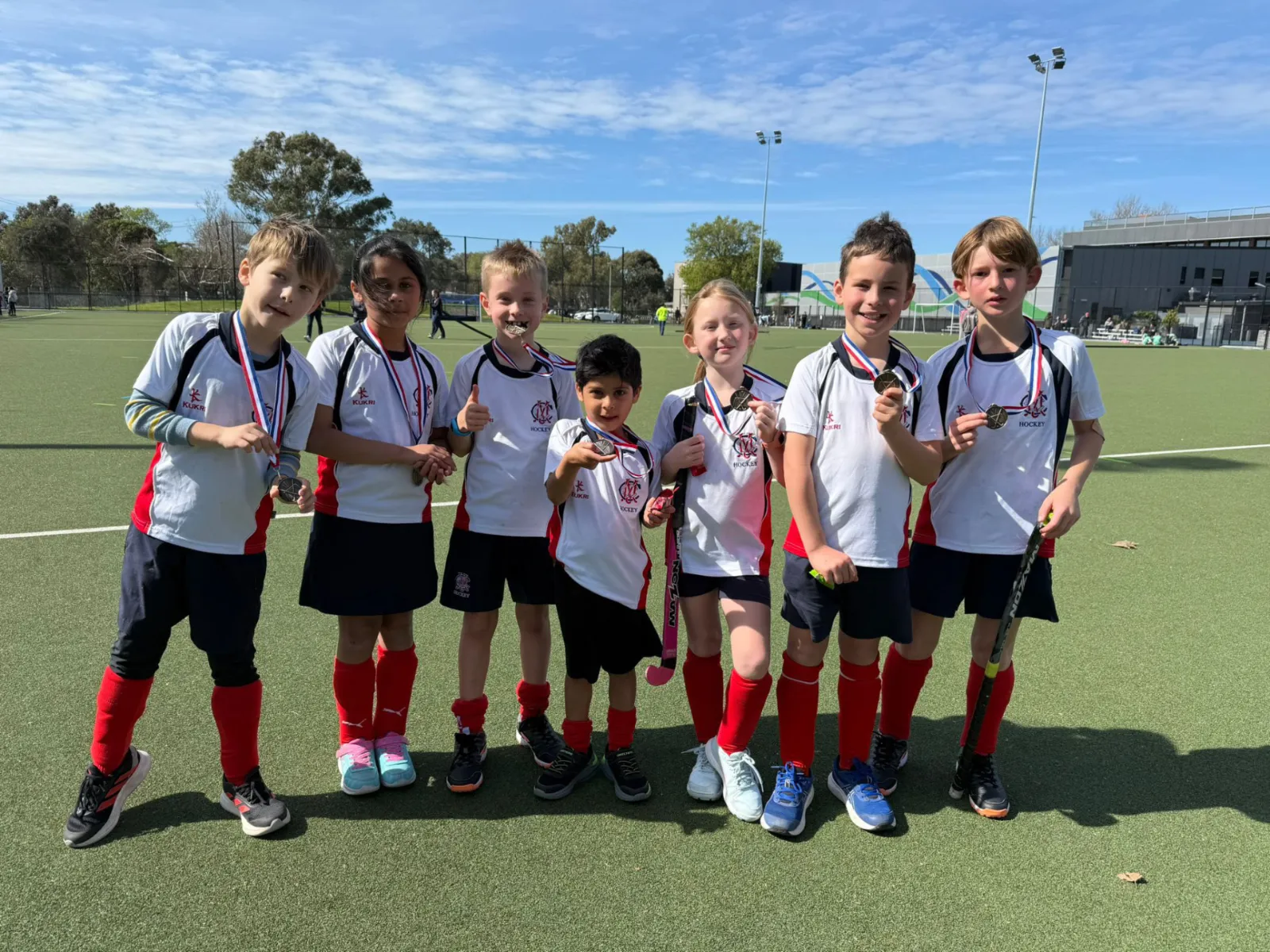 Kids posing with medals at a hockey event